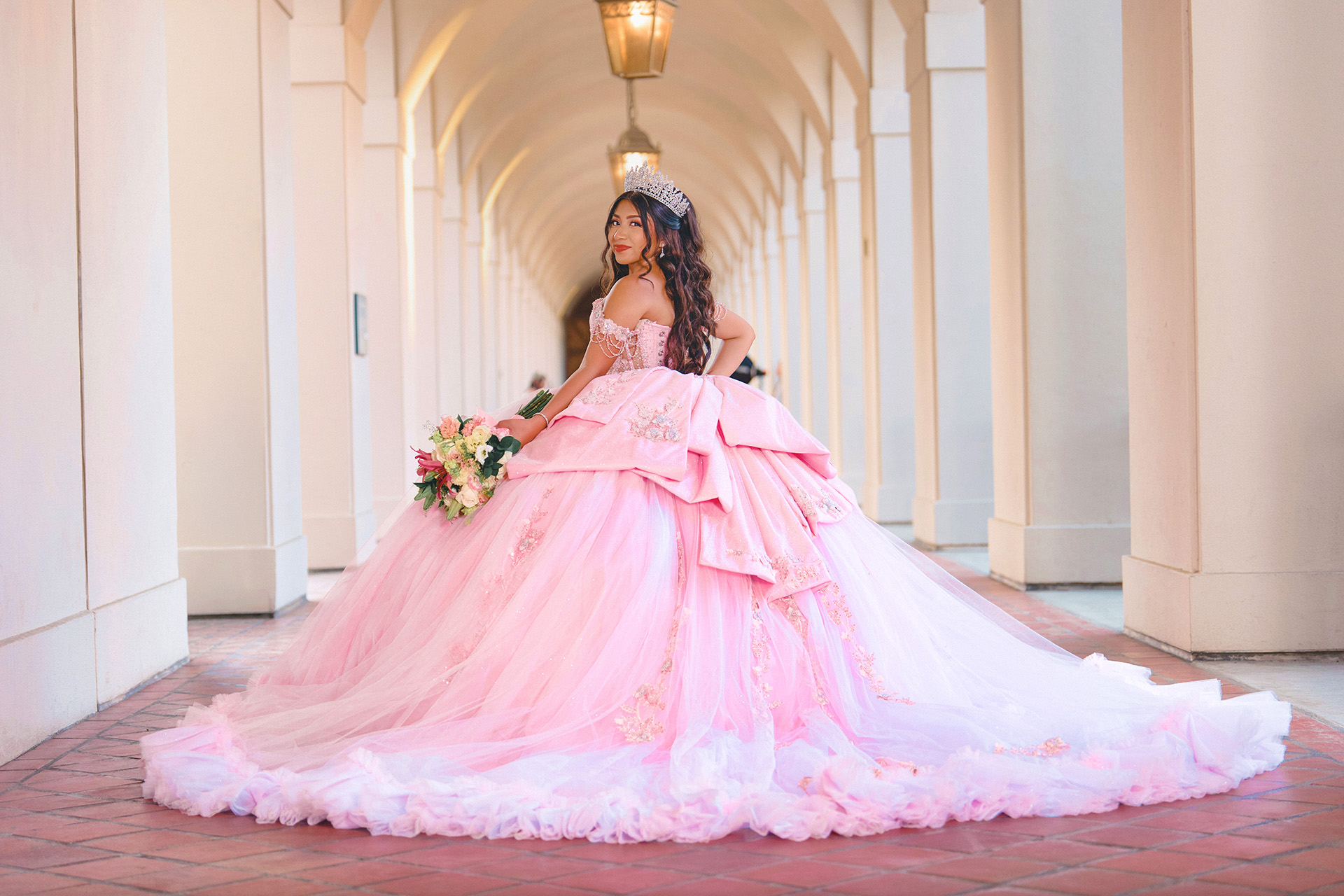 Quinceañera in pink ballgown in a sunlit corridor
