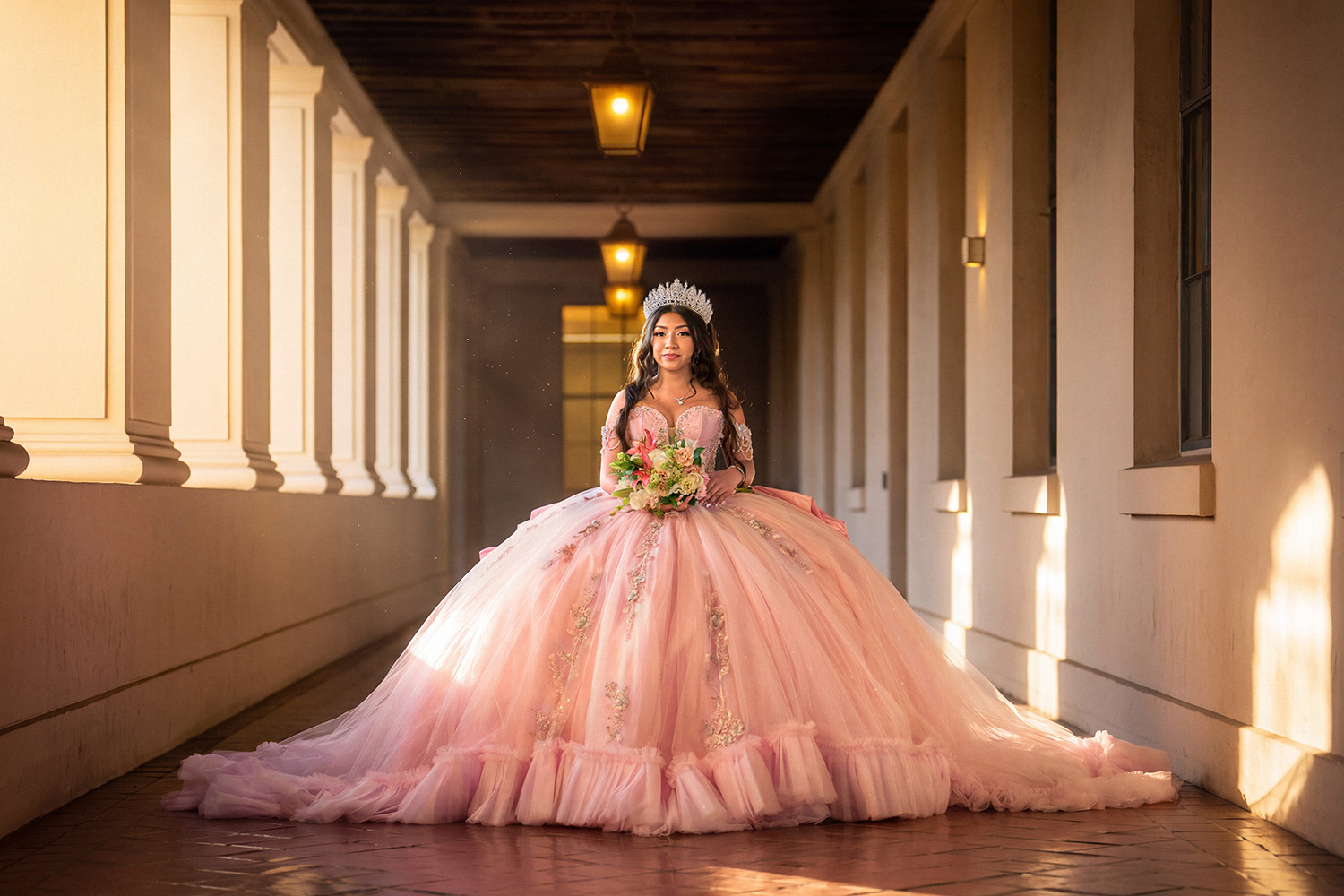 Quinceañera in pink ballgown in a sunlit corridor