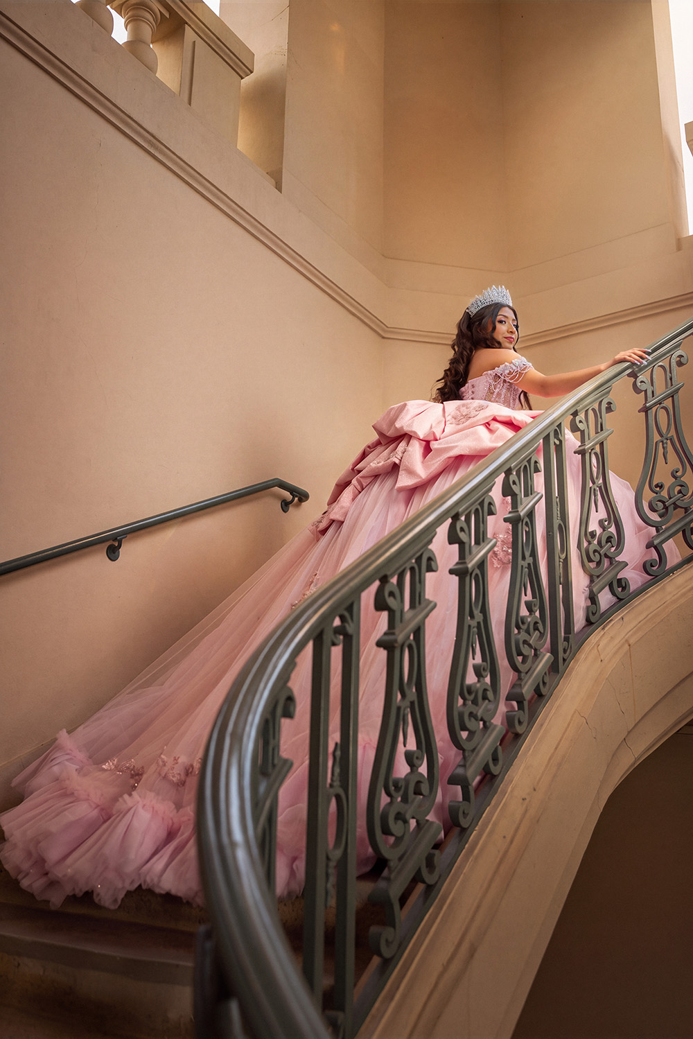 Quinceañera in pink ballgown on a curved staircase